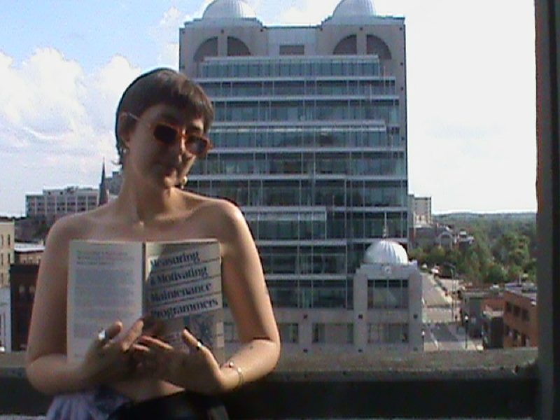 SADiE holding a book in front of their chest, with the domes in the background