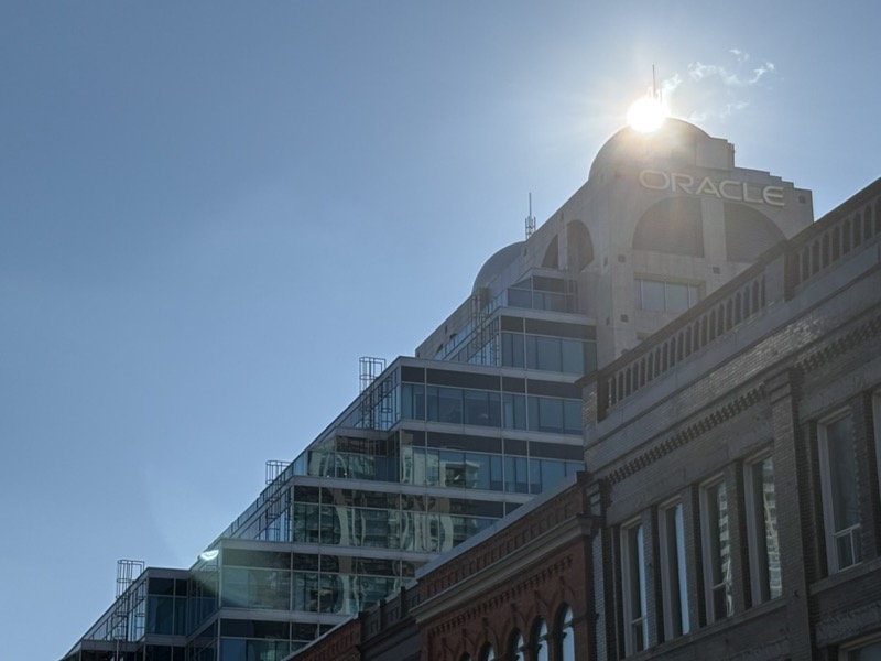 Silhouette of the building against a bright blue sky, the sun peeking out from the top of the dome.