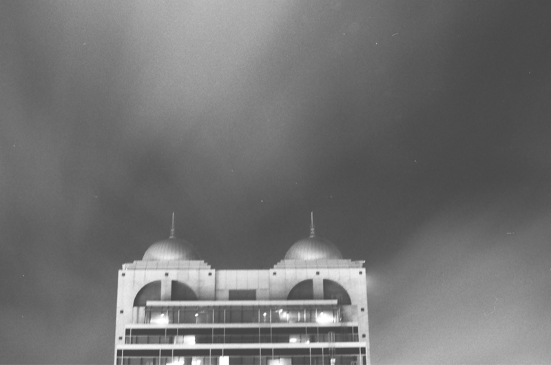 Greyscale photo of the Canada Trust building silhouetted against a dark cloudy sky.